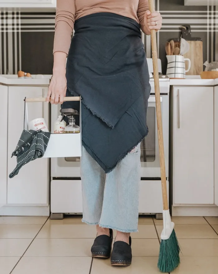 A cleaner sweeping the floor of a tidy Nottingham kitchen.