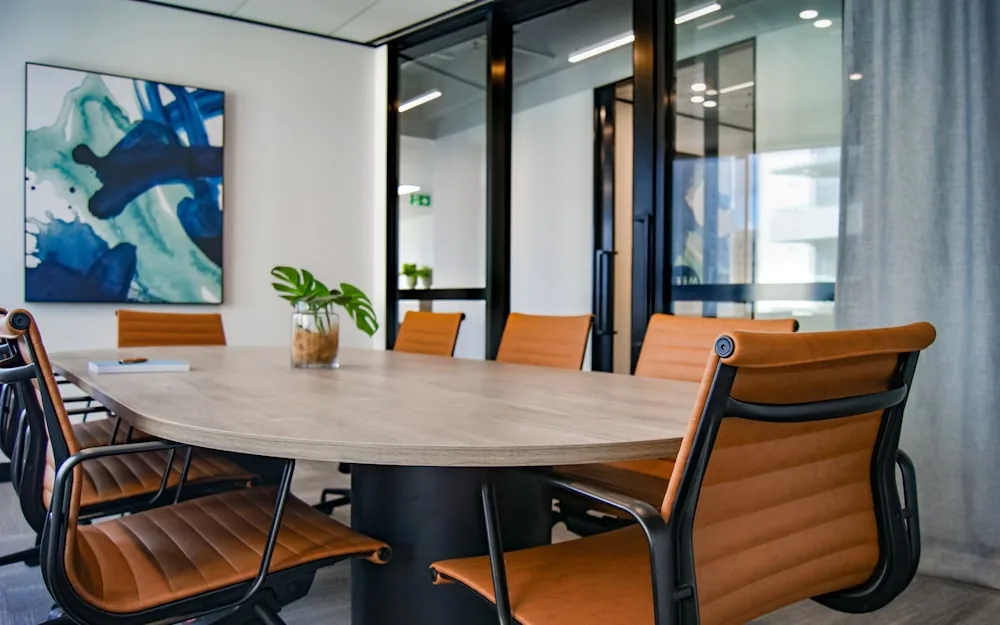 A clean office meeting room with a polished table and chairs.