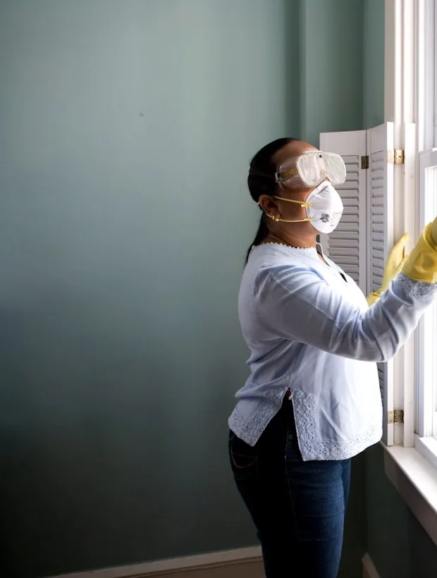A cleaner wiping down a large window.